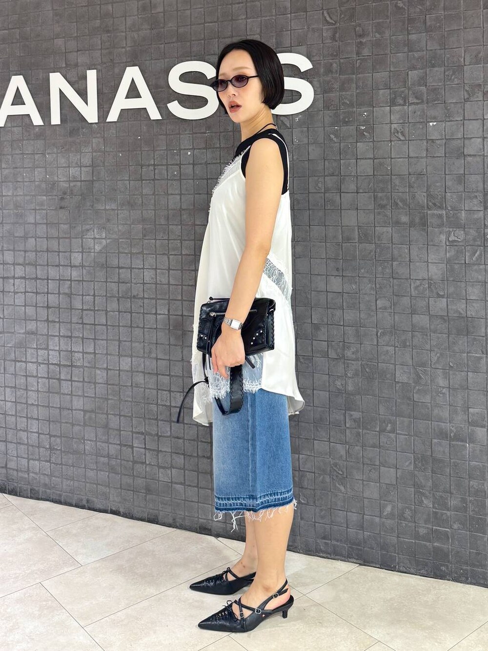 ブラック系のパンプス、ブルー系のデニムパンツ、ブラック系のTシャツ/カットソーを着用したレディースの夏コーディネートの2枚目の写真