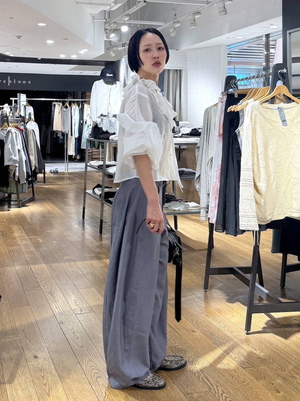 ブラック系のボストンバッグ、ベージュ系のローファー、グレー系のスラックスを着用したレディースの春コーディネートの3枚目の写真