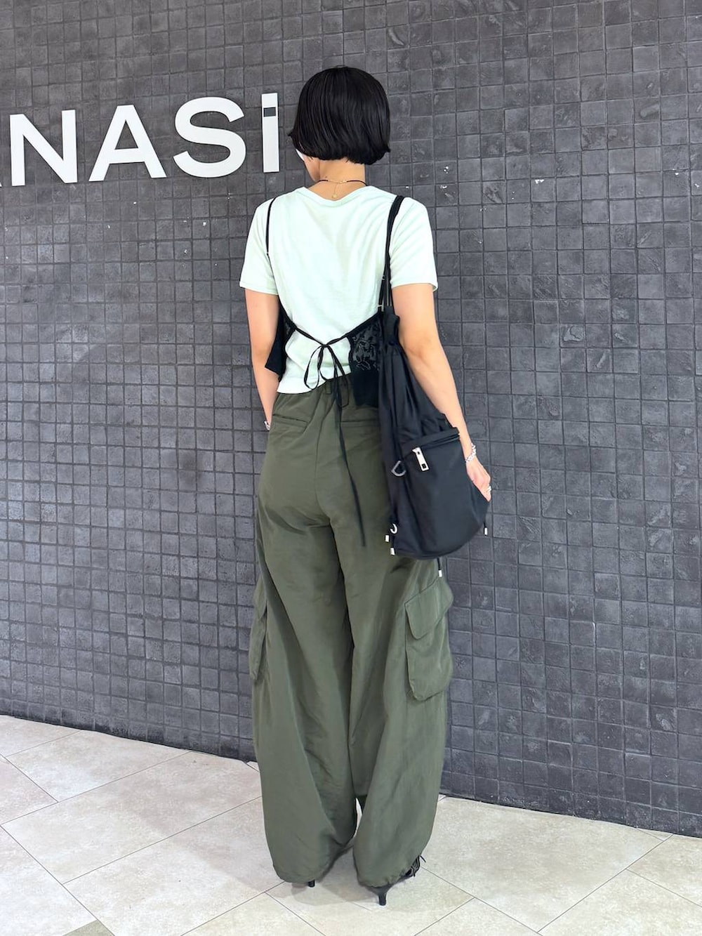 ブラック系のパンプス、グリーン系のTシャツ/カットソー、ブラック系のサングラスを着用したレディースの夏コーディネートの3枚目の写真
