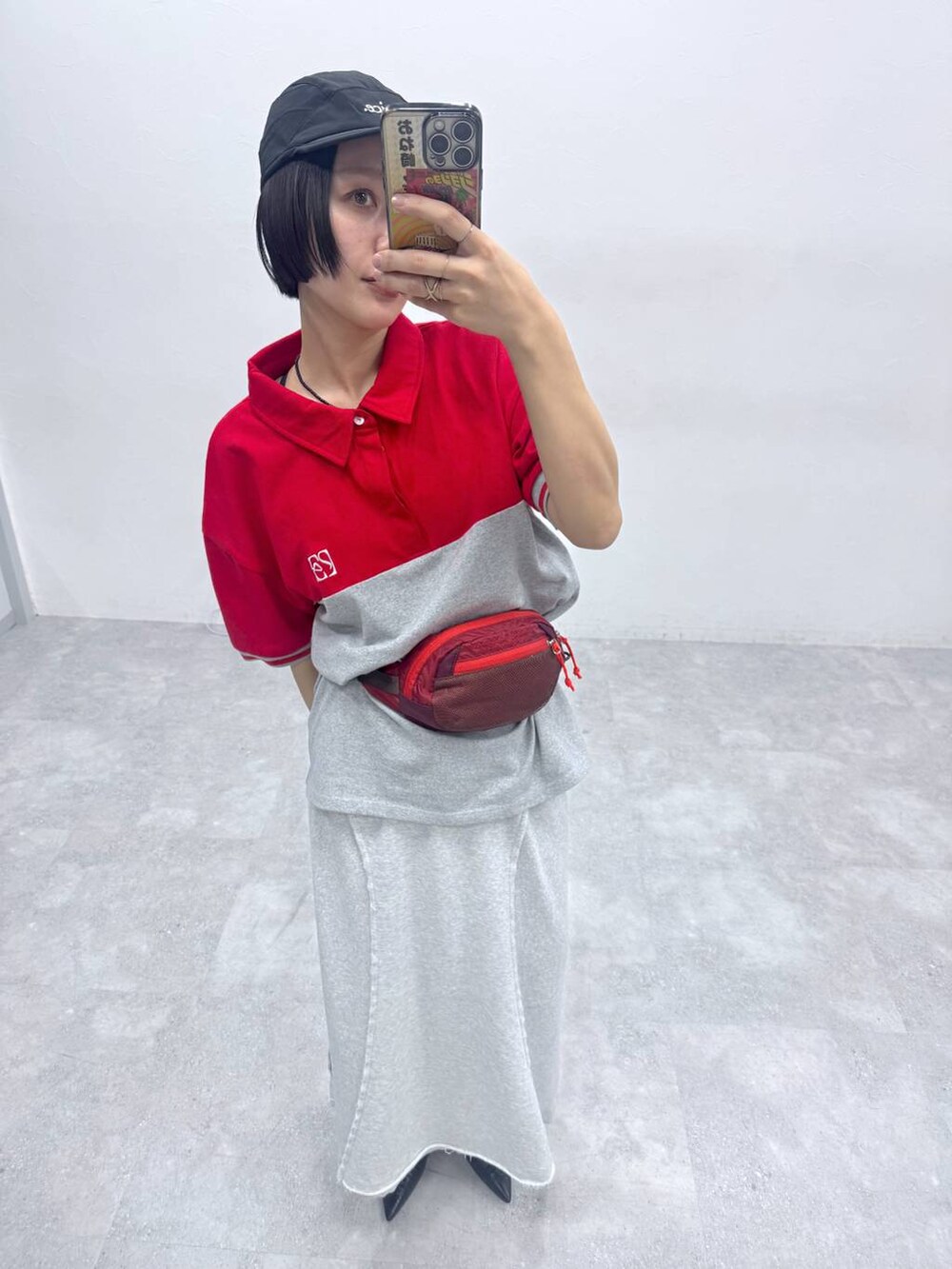 グレー系のスカート、レッド系のポロシャツを着用したレディースの春コーディネートの2枚目の写真