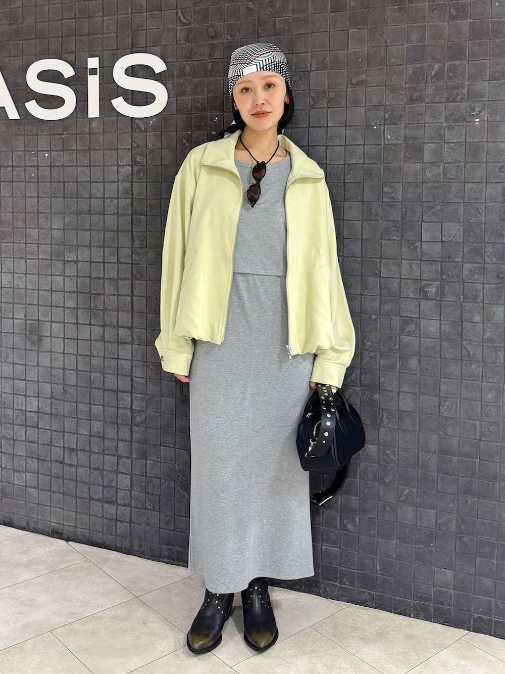 ブラック系のボストンバッグ、ブラック系のブーツ、グレー系のワンピースを着用したレディースの春コーディネートの6枚目の写真