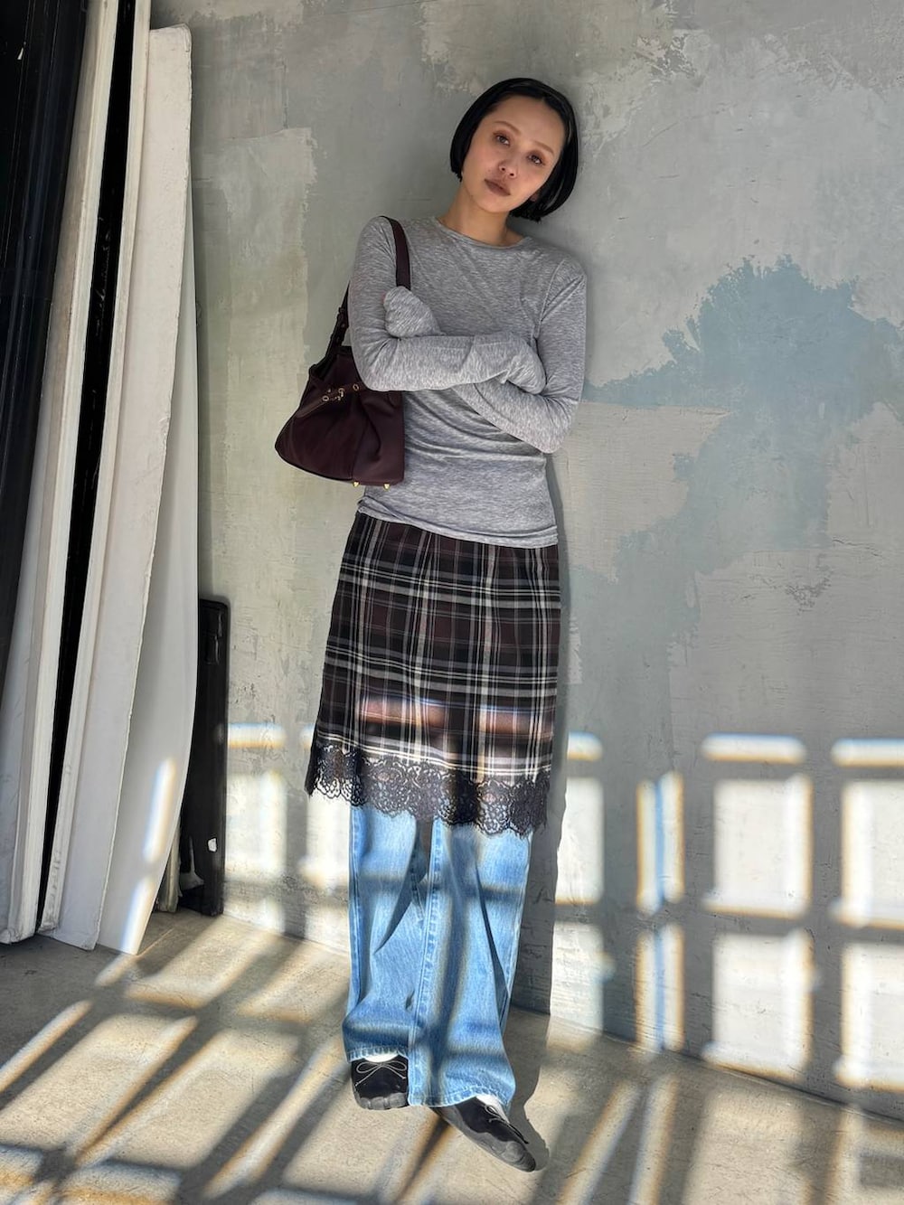 グレー系のTシャツ/カットソー、レッド系のショルダーバッグ、ブルー系のデニムパンツを着用したレディースの秋コーディネートの2枚目の写真