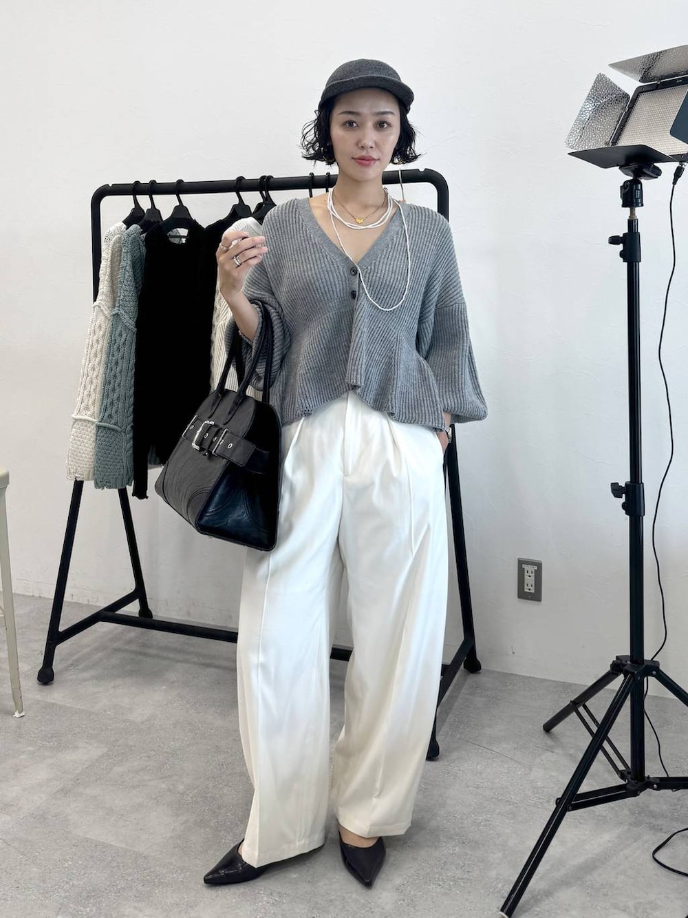 ホワイト系のスラックス、ブラック系のショルダーバッグ、グレー系のカーディガン/ボレロを着用したレディースの秋コーディネートの7枚目の写真