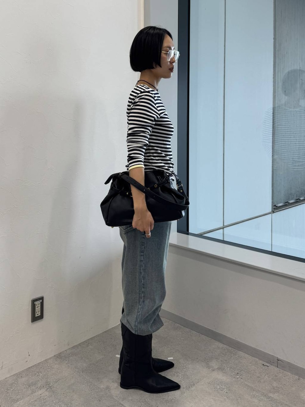 ブルー系のデニムパンツ、ブラック系のショルダーバッグ、ブラック系のブーツを着用したレディースの夏コーディネートの2枚目の写真