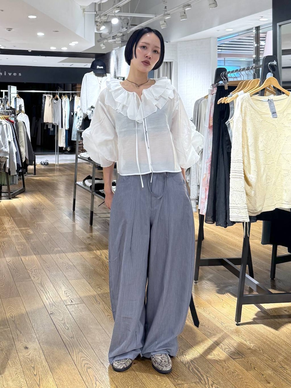 ブラック系のボストンバッグ、ベージュ系のローファー、グレー系のスラックスを着用したレディースの春コーディネートの4枚目の写真