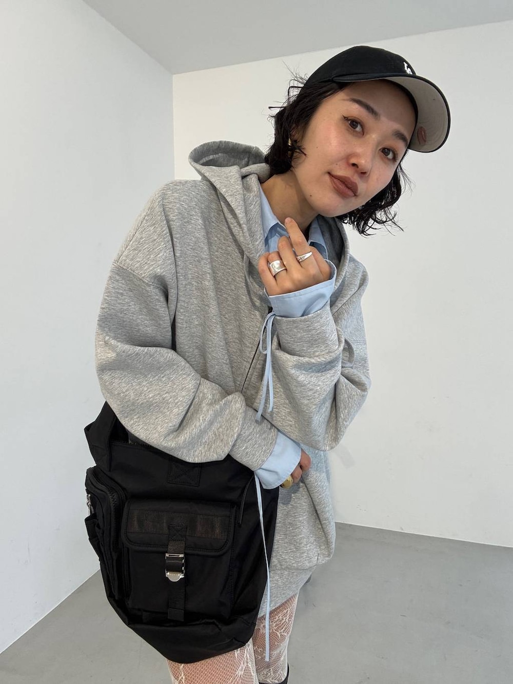 ブラック系のブーツ、ブラック系のトートバッグ、グレー系のパーカーを着用したレディースの冬コーディネートの2枚目の写真