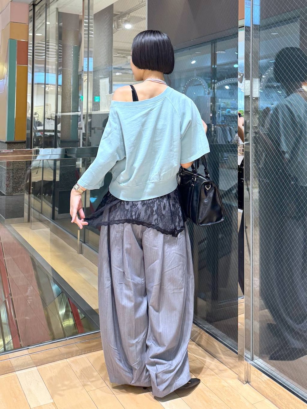 ブラック系のパンプス、ブラック系のボストンバッグ、グレー系のスラックスを着用したレディースの春コーディネートの4枚目の写真