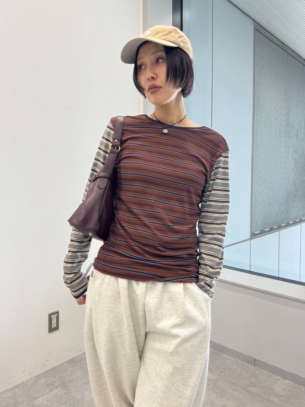 レッド系のショルダーバッグ、ホワイト系のブーツ、ベージュ系のスウェットパンツを着用したレディースの夏コーディネートの5枚目の写真