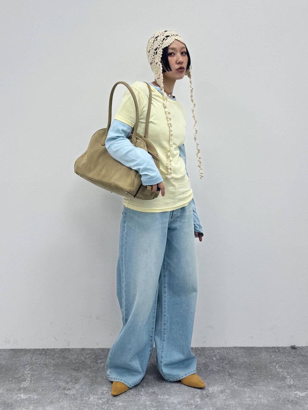 ベージュ系のショルダーバッグ、ベージュ系のパンプス、ブルー系のデニムパンツを着用したレディースの冬コーディネートの4枚目の写真