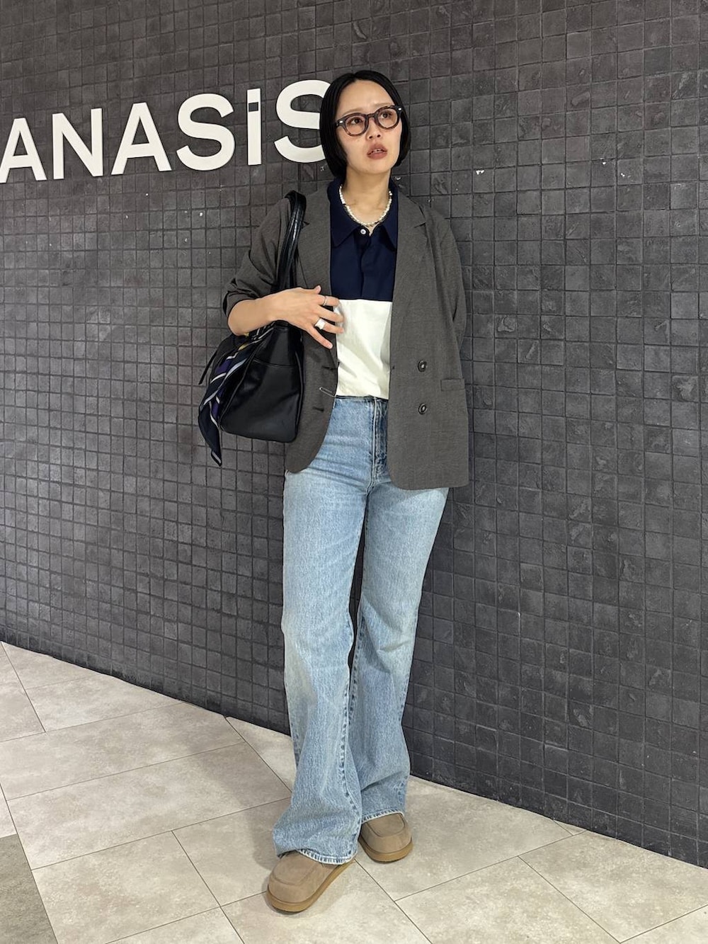 ブルー系のデニムパンツ、ベージュ系のローファー、ブラック系のトートバッグを着用したレディースの春コーディネートの6枚目の写真