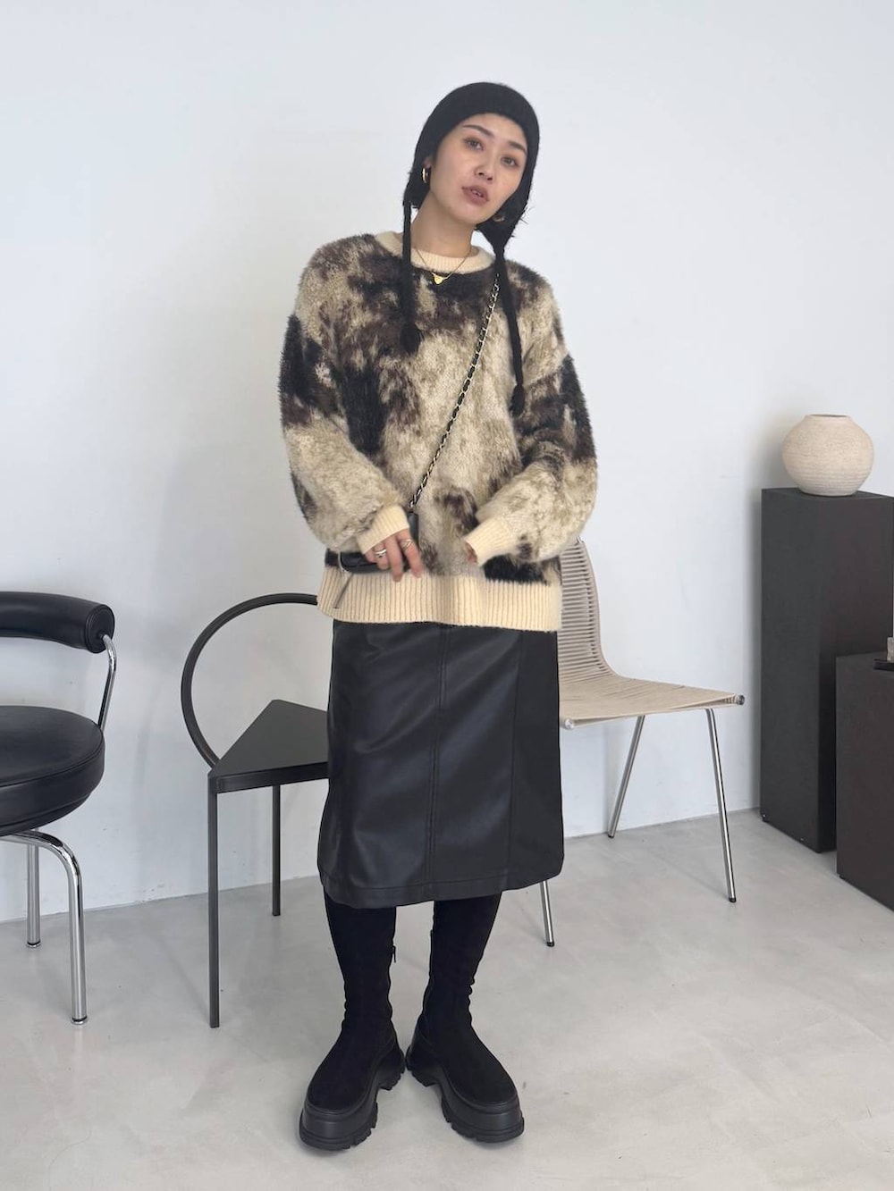 ブラウン系のニット/セーター、ブラック系のブーツ、ブラック系のスカートを着用したレディースの秋コーディネートの6枚目の写真