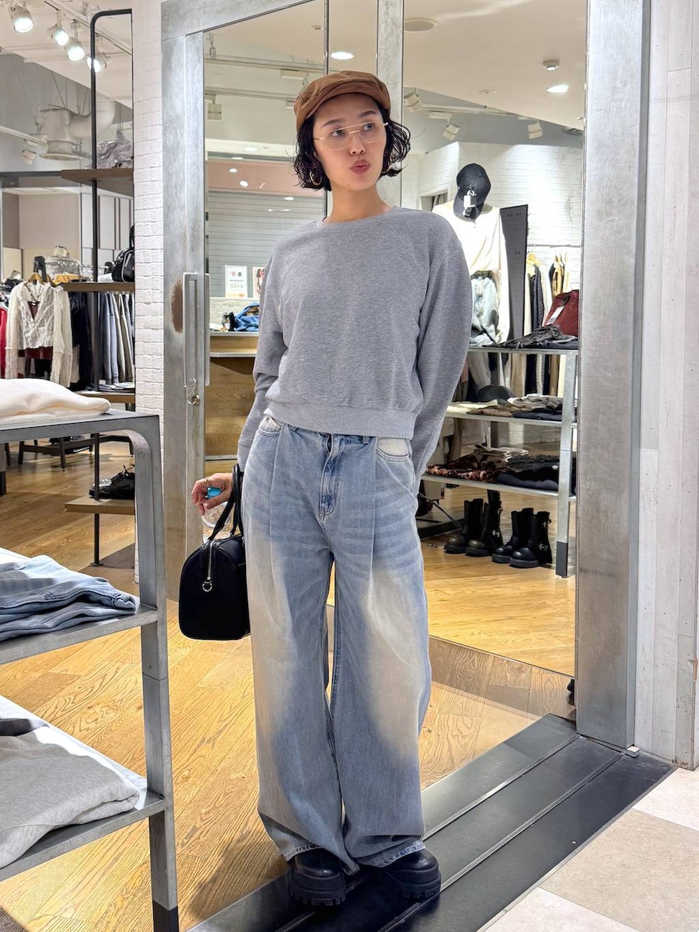 グリーン系のボストンバッグ、ブルー系のデニムパンツ、ブラック系のブーツを着用したレディースの秋コーディネートの2枚目の写真