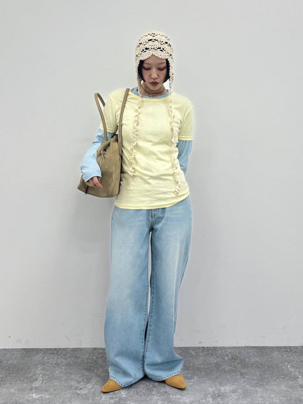 ベージュ系のショルダーバッグ、ベージュ系のパンプス、ブルー系のデニムパンツを着用したレディースの冬コーディネートの2枚目の写真