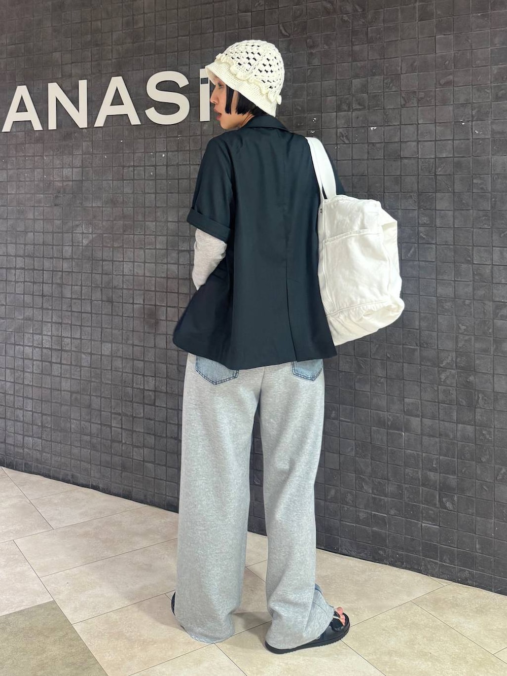 ブルー系のデニムパンツ、ホワイト系のショルダーバッグ、ブラック系のサンダルを着用したレディースの春コーディネートの5枚目の写真