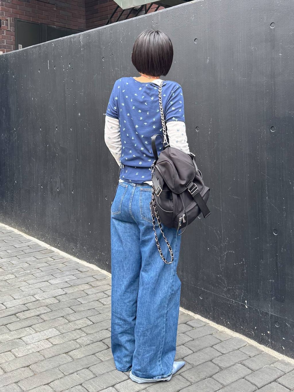 ブラック系のバックパック/リュック、ブルー系のTシャツ/カットソー、ブラウン系のベルトを着用したレディースの春コーディネートの4枚目の写真