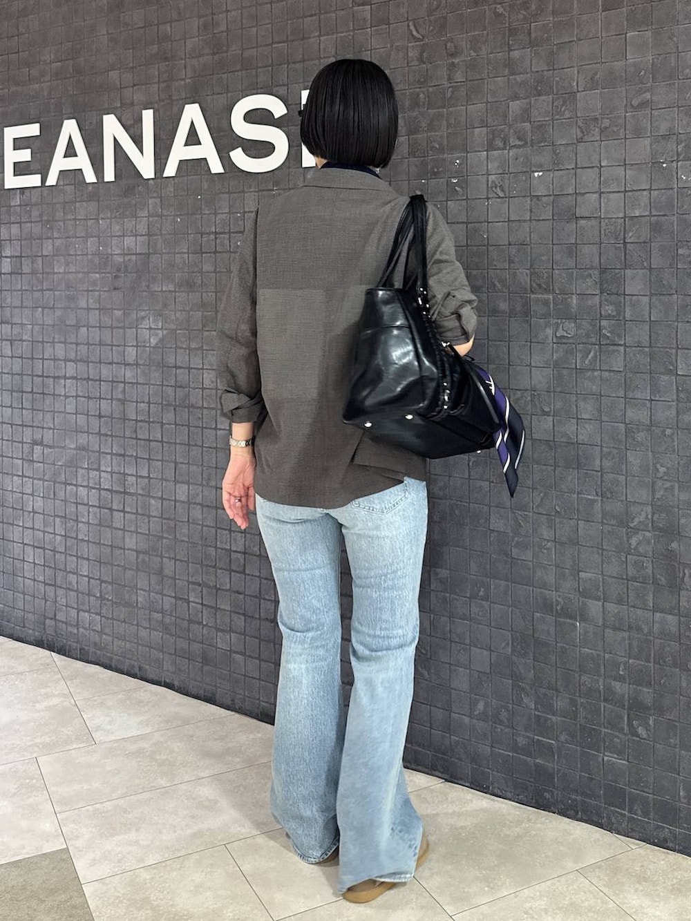 ブルー系のデニムパンツ、ベージュ系のローファー、ブラック系のトートバッグを着用したレディースの春コーディネートの4枚目の写真