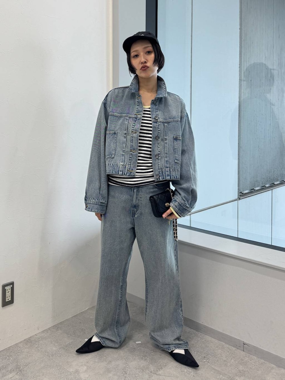ブルー系のデニムジャケット、ブルー系のデニムパンツ、ブラック系のサンダルを着用したレディースの夏コーディネートの5枚目の写真