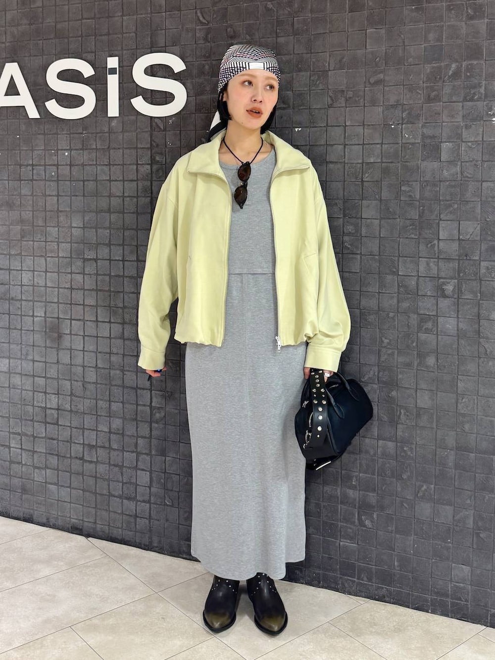 ブラック系のボストンバッグ、ブラック系のブーツ、グレー系のワンピースを着用したレディースの春コーディネートの5枚目の写真