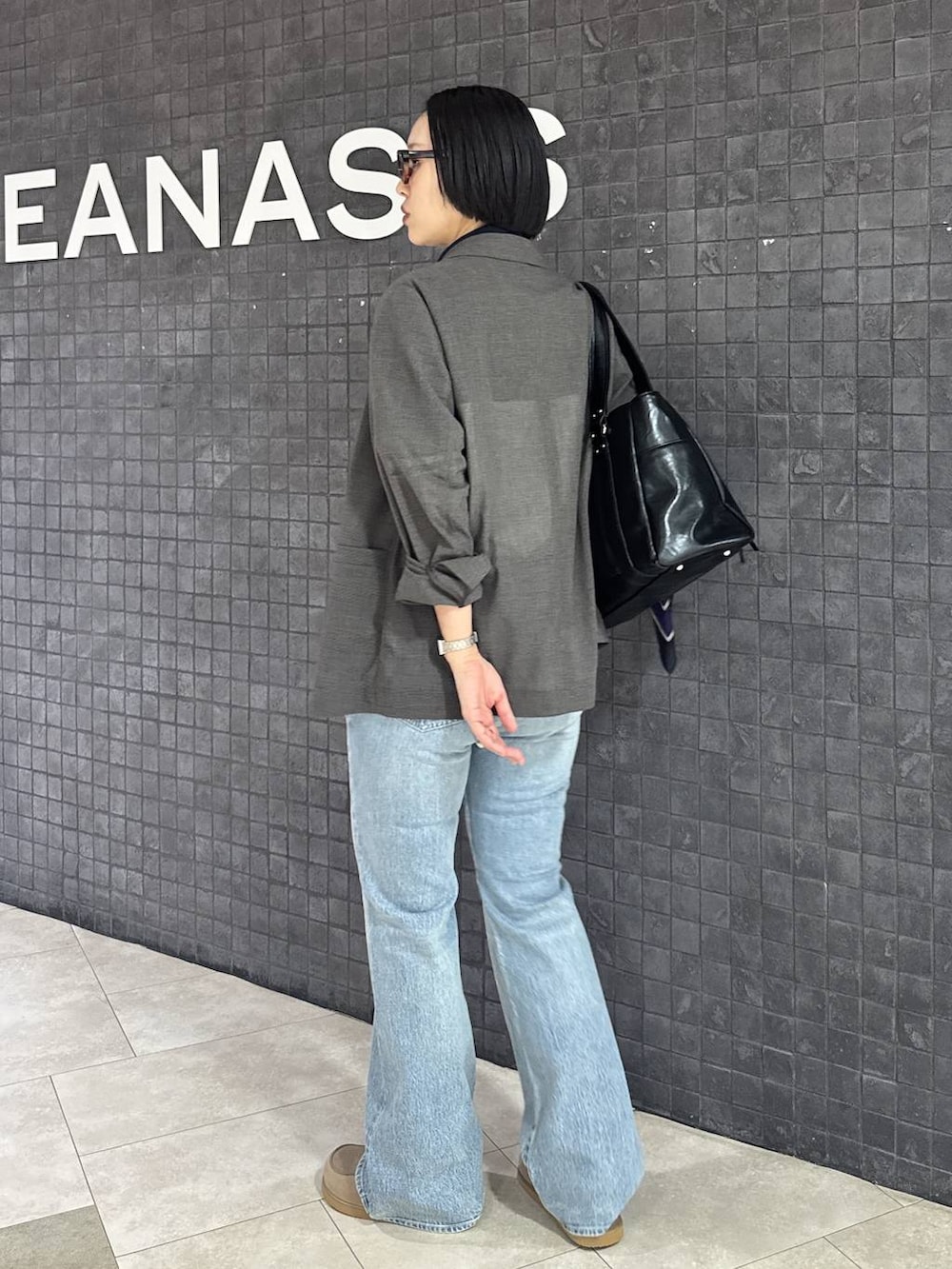 ブルー系のデニムパンツ、ベージュ系のローファー、ブラック系のトートバッグを着用したレディースの春コーディネートの5枚目の写真