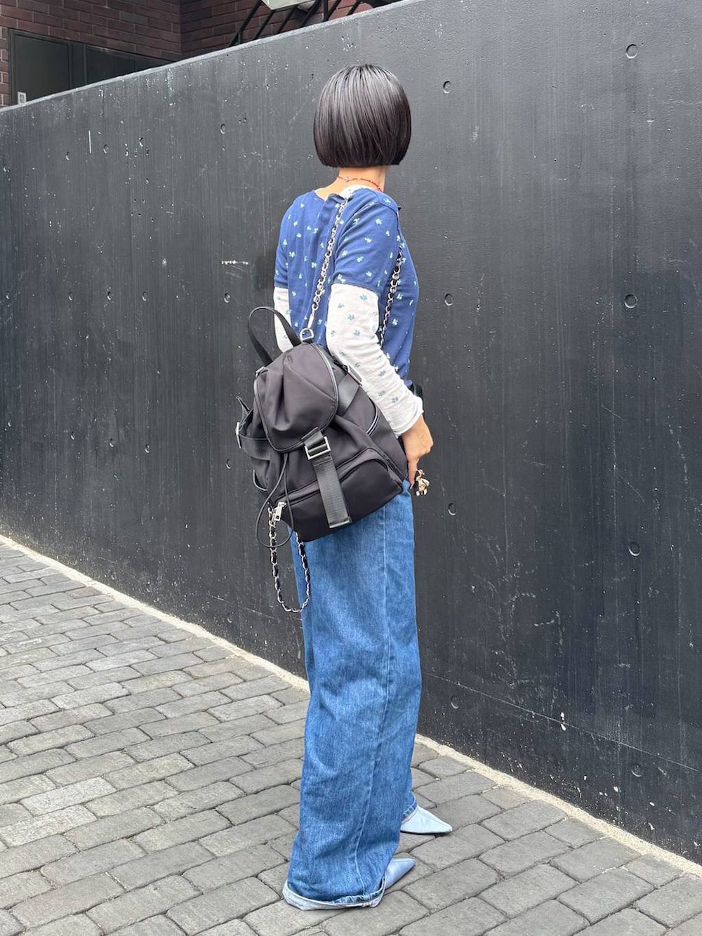 ブラック系のバックパック/リュック、ブルー系のTシャツ/カットソー、ブラウン系のベルトを着用したレディースの春コーディネートの5枚目の写真