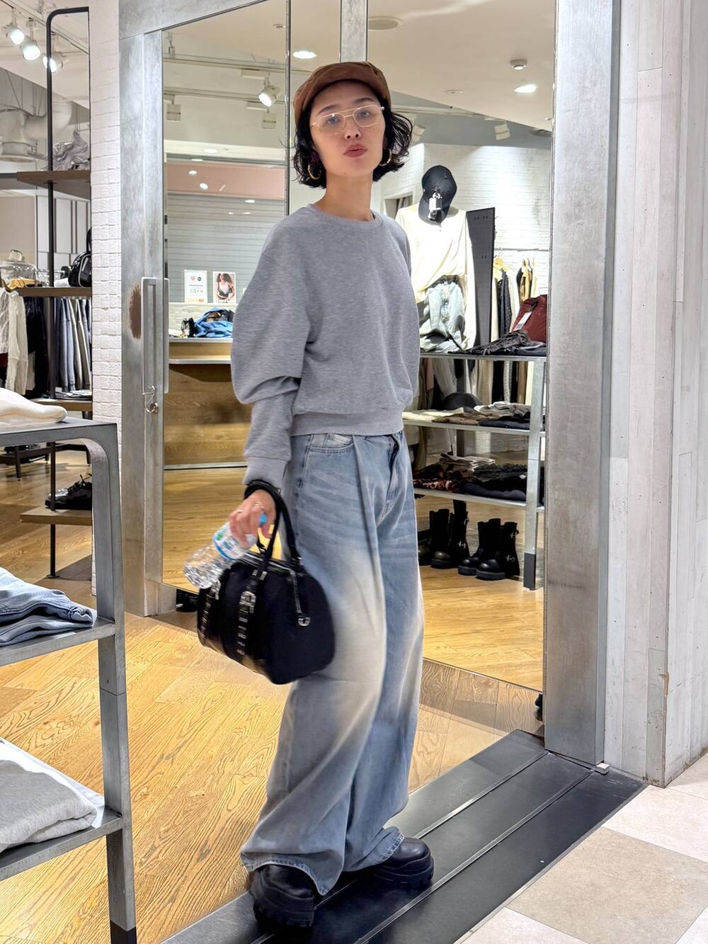 グリーン系のボストンバッグ、ブルー系のデニムパンツ、ブラック系のブーツを着用したレディースの秋コーディネートの3枚目の写真