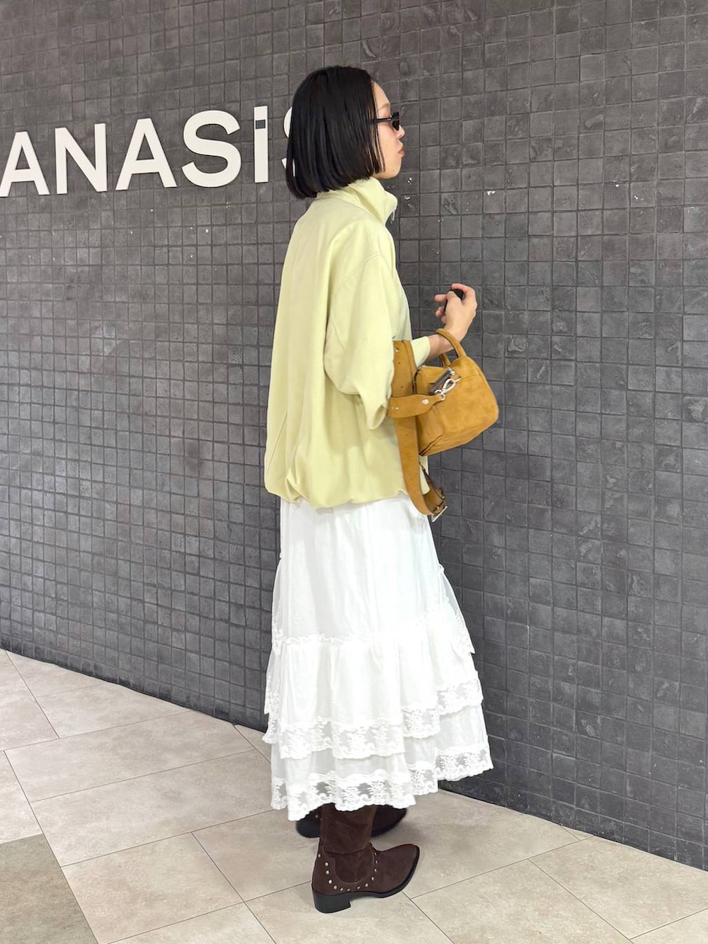 ブラウン系のボストンバッグ、ブラウン系のブーツ、ホワイト系のスカートを着用したレディースの春コーディネートの3枚目の写真