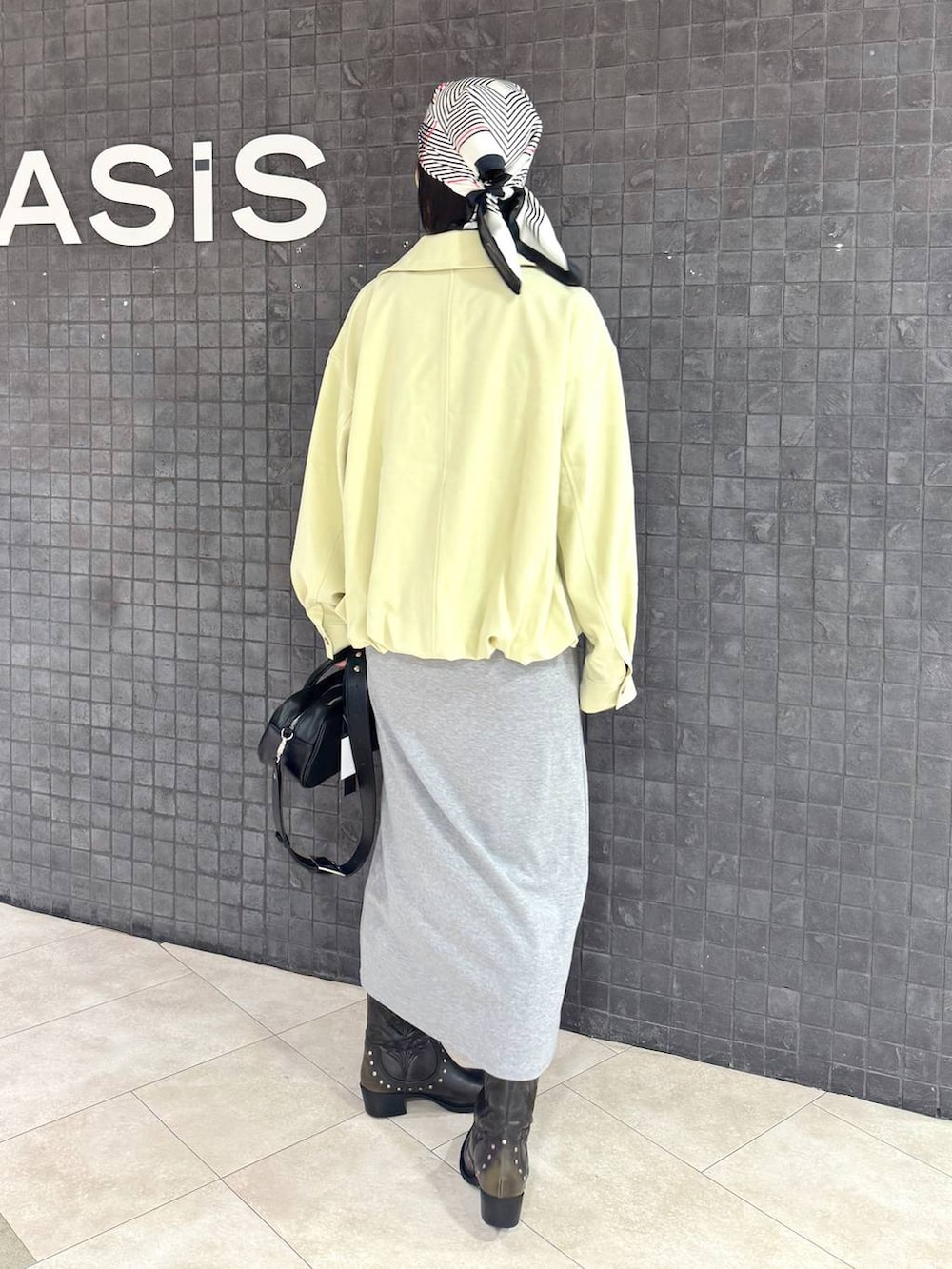 ブラック系のボストンバッグ、ブラック系のブーツ、グレー系のワンピースを着用したレディースの春コーディネートの4枚目の写真