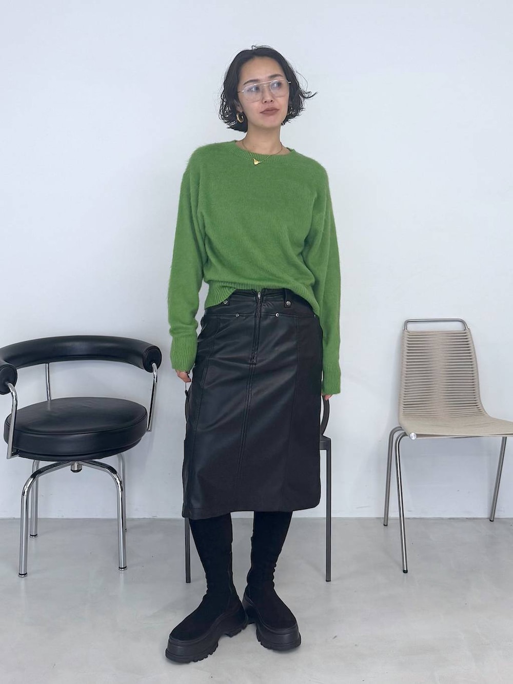 ブラック系のブーツ、グリーン系のニット/セーター、ブラック系のスカートを着用したレディースの秋コーディネートの5枚目の写真