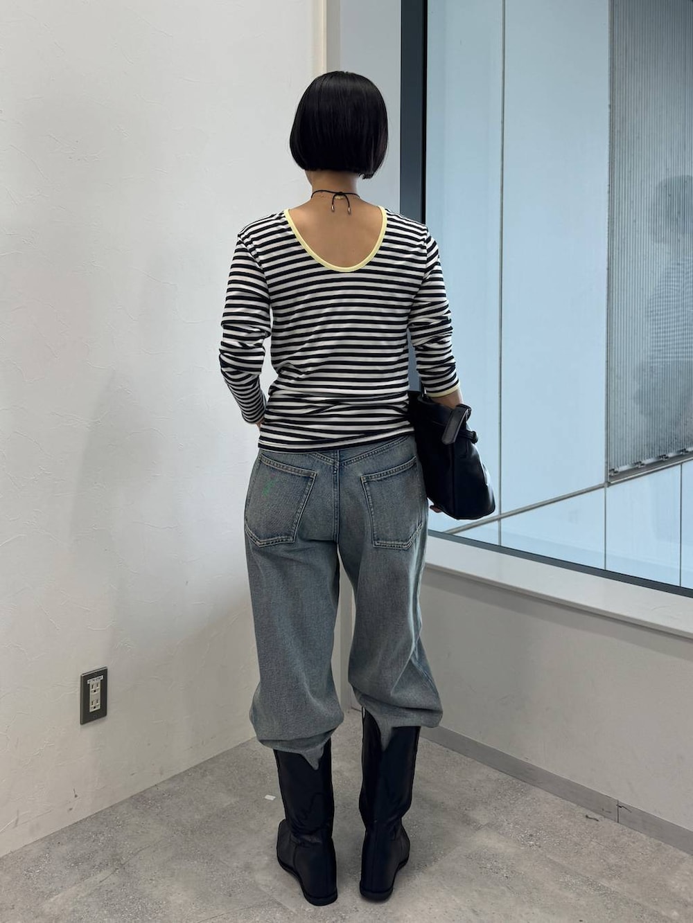 ブルー系のデニムパンツ、ブラック系のショルダーバッグ、ブラック系のブーツを着用したレディースの夏コーディネートの3枚目の写真