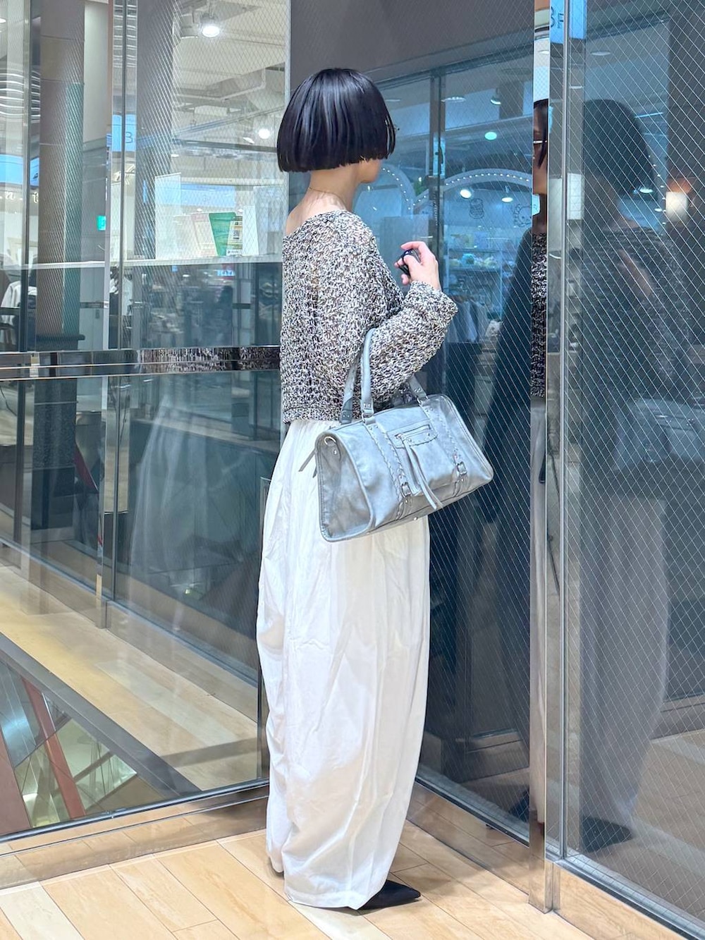 ブラック系のパンプス、ブルー系のボストンバッグ、ブラック系のニット/セーターを着用したレディースの春コーディネートの5枚目の写真