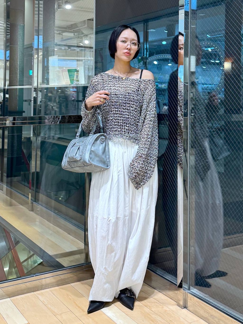 ブラック系のパンプス、ブルー系のボストンバッグ、ブラック系のニット/セーターを着用したレディースの春コーディネートの6枚目の写真