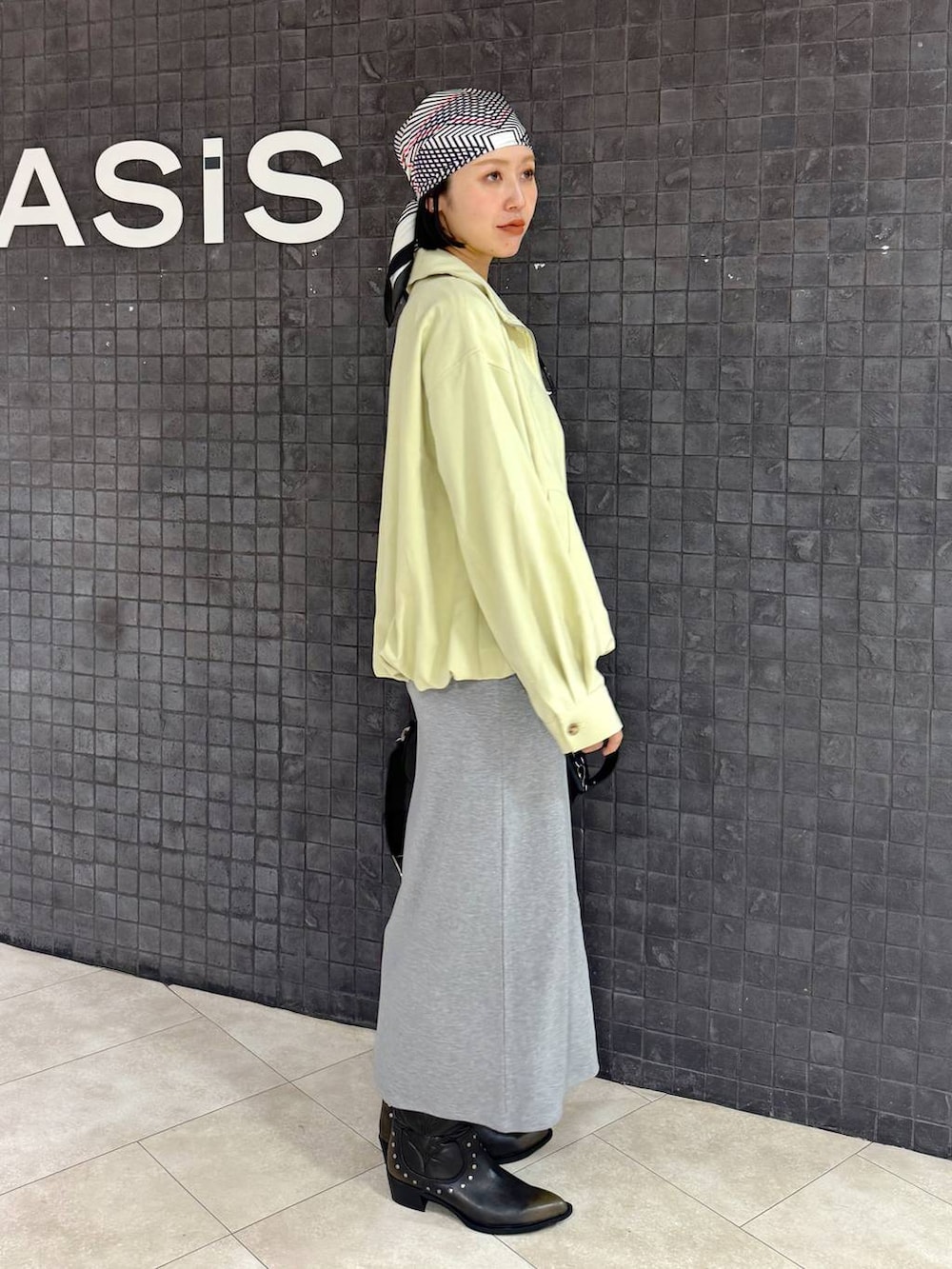 ブラック系のボストンバッグ、ブラック系のブーツ、グレー系のワンピースを着用したレディースの春コーディネートの3枚目の写真