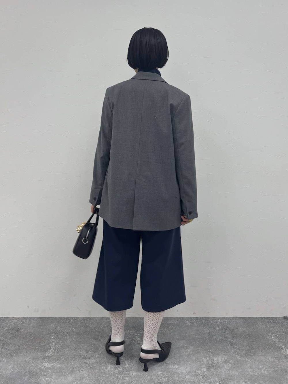 ブラック系のローファー、ブラック系のショルダーバッグ、グレー系のテーラードジャケットを着用したレディースの冬コーディネートの4枚目の写真