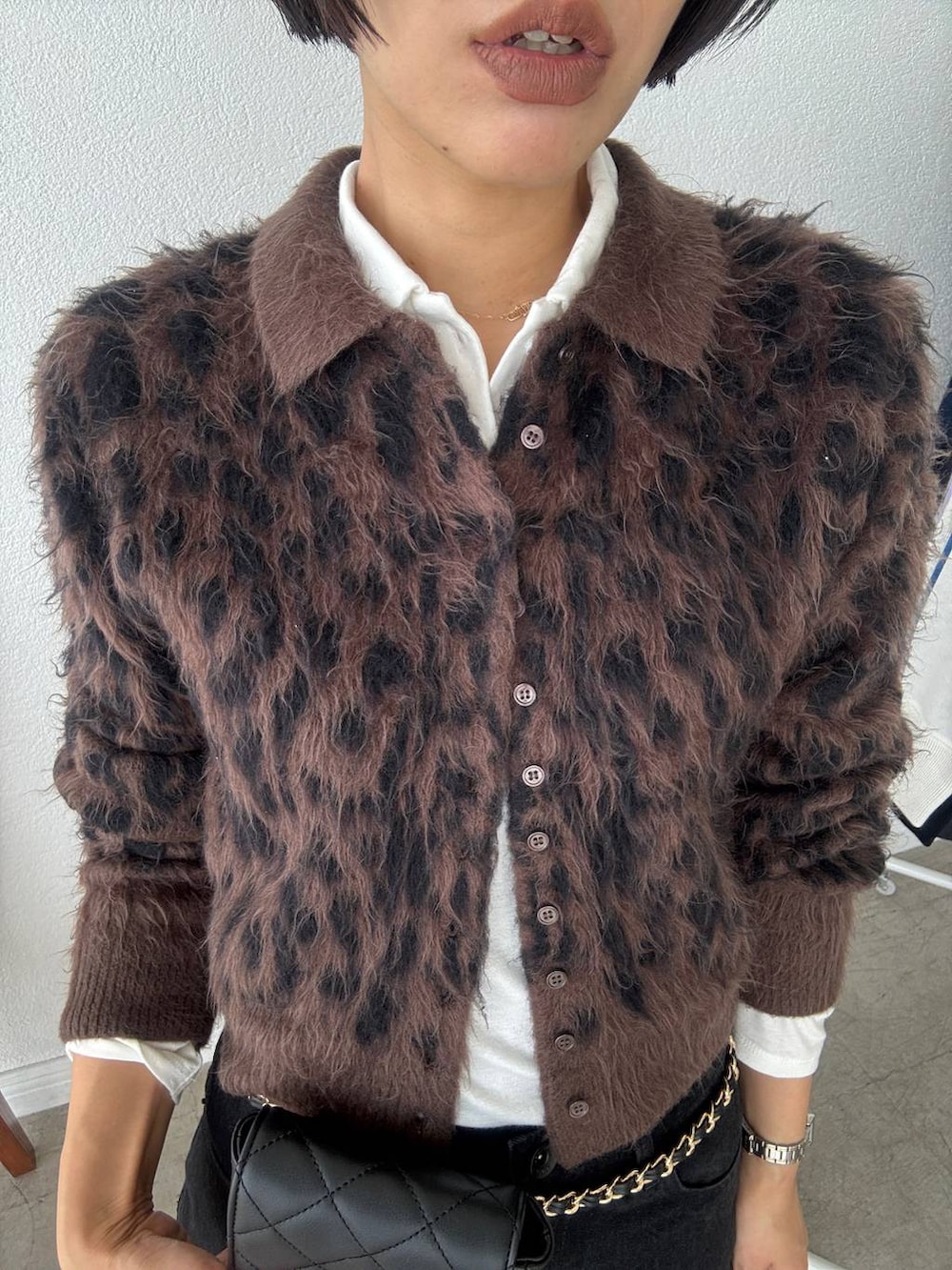 ブラック系のデニムパンツ、ホワイト系のポロシャツ、ブラウン系のカーディガン/ボレロを着用したレディースの秋コーディネートの4枚目の写真