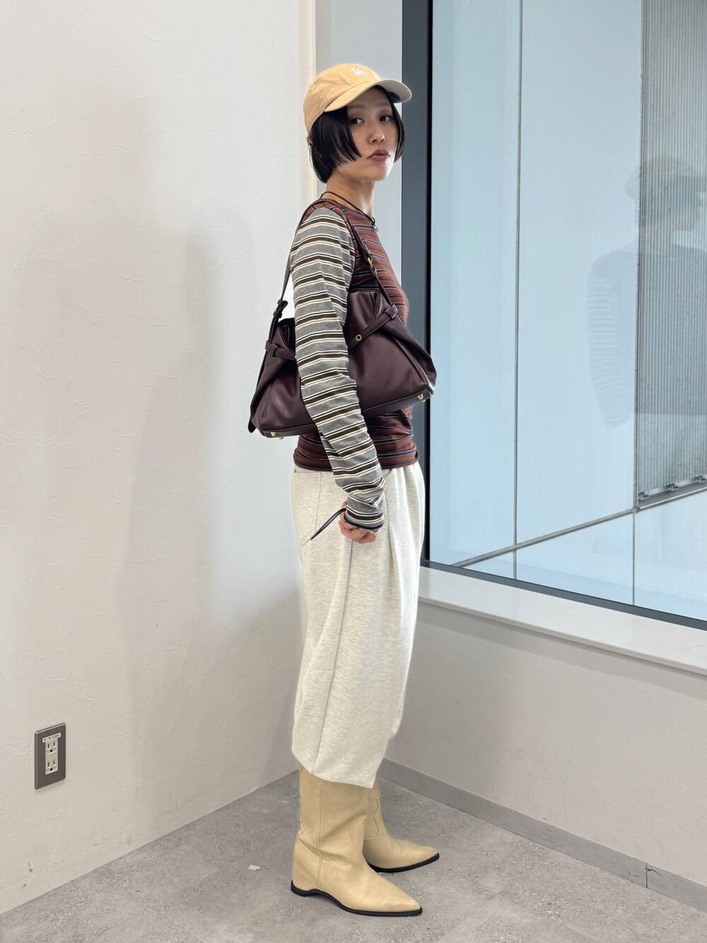 レッド系のショルダーバッグ、ホワイト系のブーツ、ベージュ系のスウェットパンツを着用したレディースの夏コーディネートの3枚目の写真