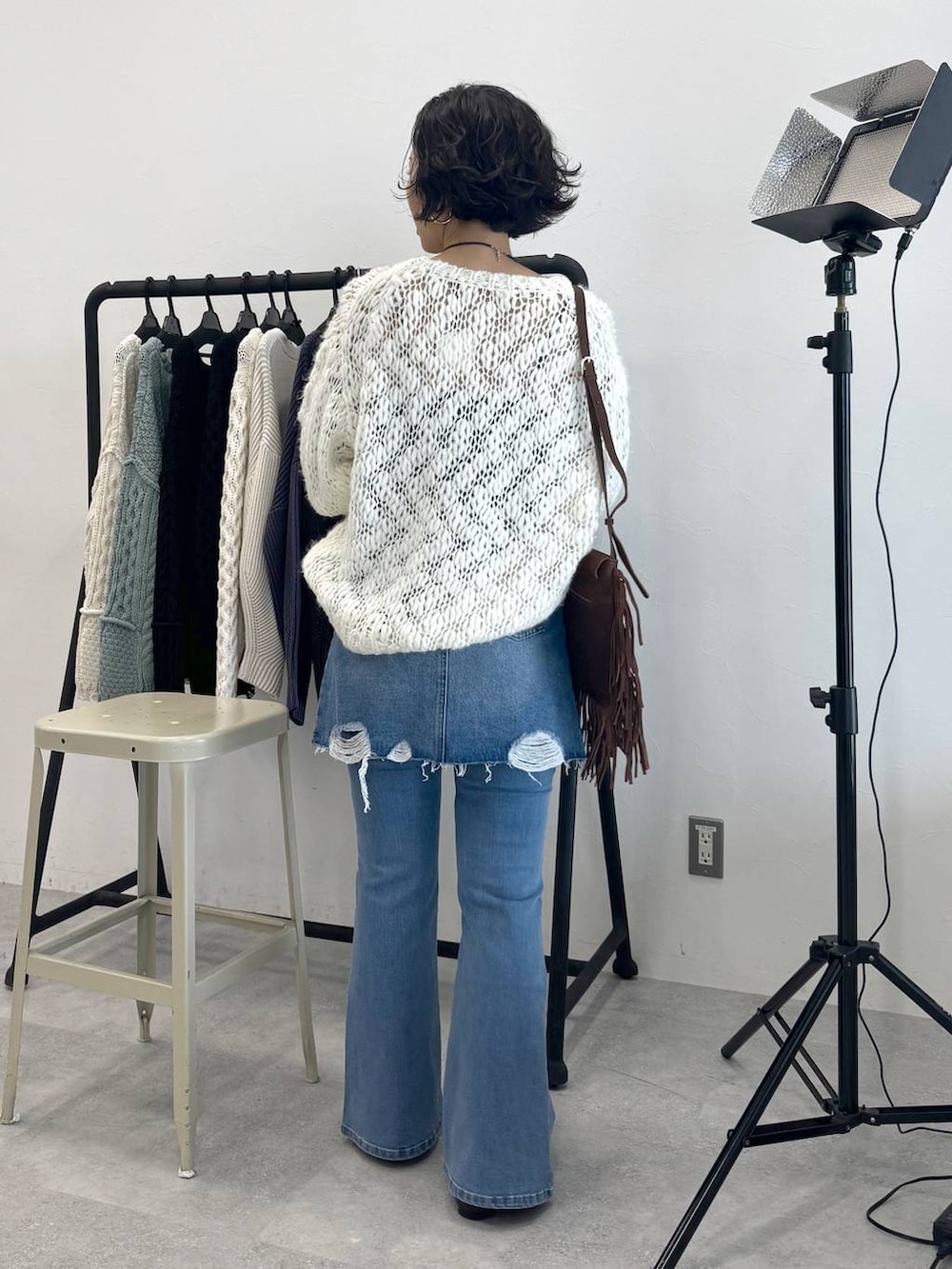 ブラウン系のショルダーバッグ、ブルー系のデニムスカート、ホワイト系のニット/セーターを着用したレディースの秋コーディネートの3枚目の写真