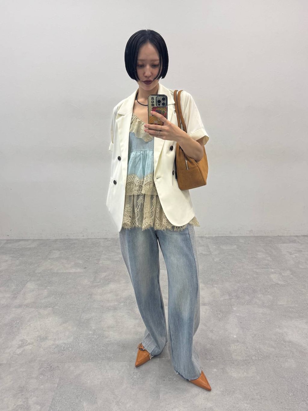 ブラウン系のボストンバッグ、ブラウン系のパンプス、ブルー系のデニムパンツを着用したレディースの春コーディネートの2枚目の写真