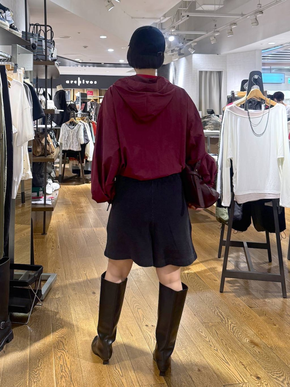 ブラック系のスウェットパンツ、ブラック系のブーツ、レッド系のショルダーバッグを着用したレディースの夏コーディネートの3枚目の写真