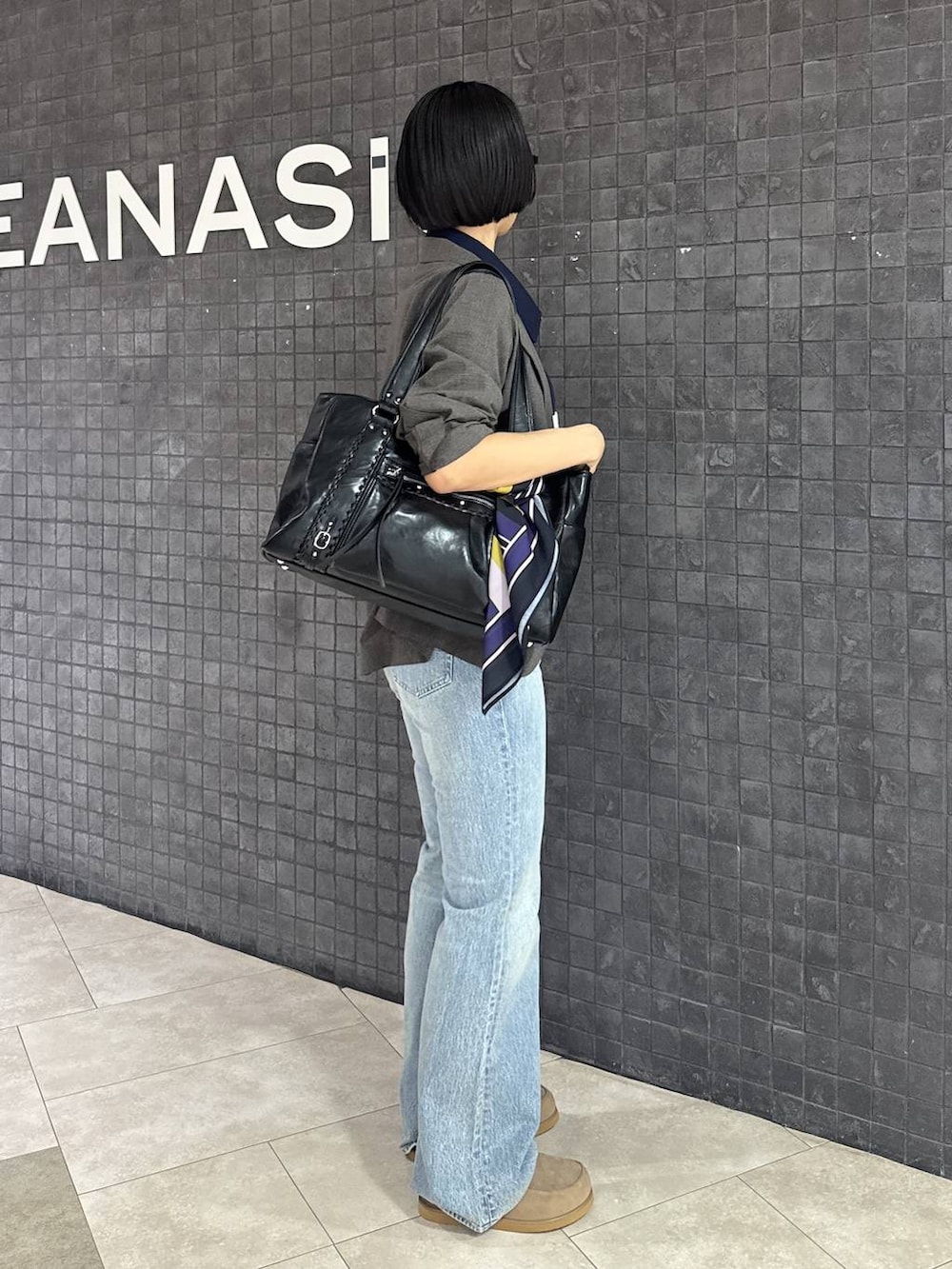 ブルー系のデニムパンツ、ベージュ系のローファー、ブラック系のトートバッグを着用したレディースの春コーディネートの3枚目の写真