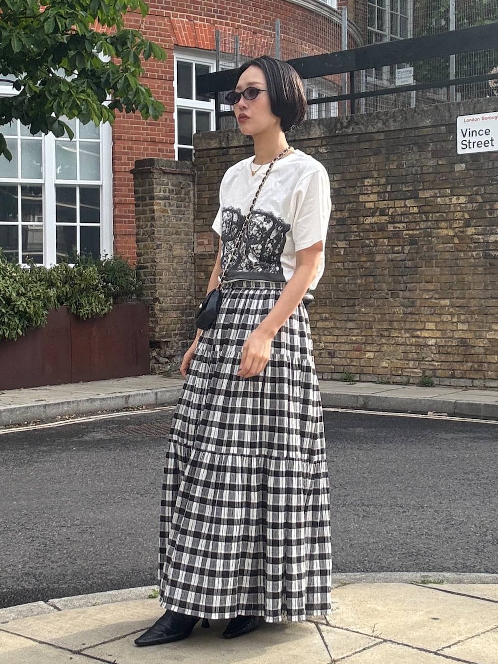 ブラック系のスカート、ホワイト系のTシャツ/カットソー、ブラック系のサングラスを着用したレディースの夏コーディネートの6枚目の写真
