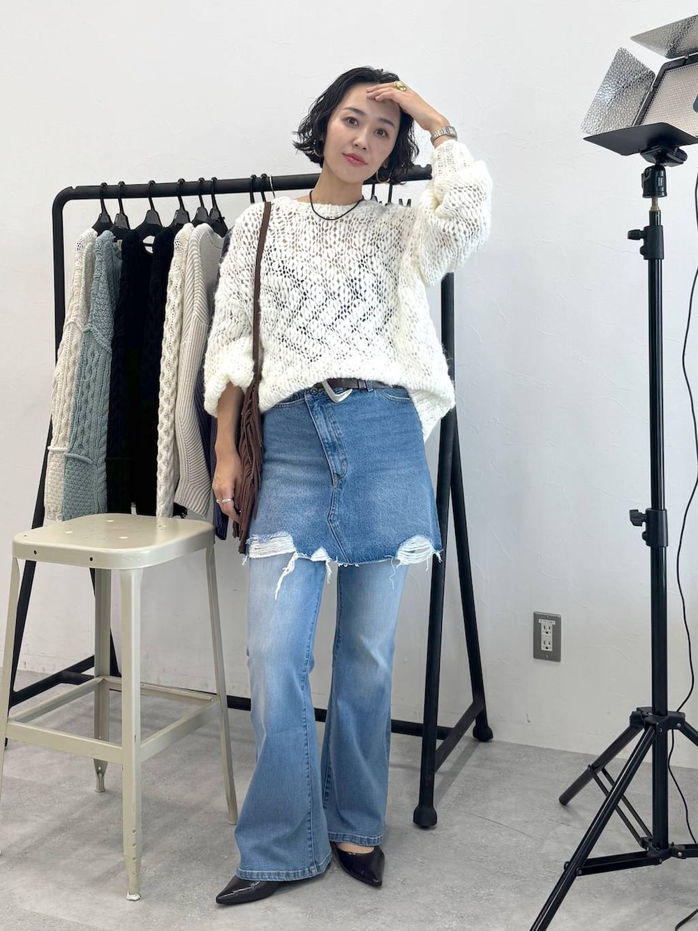 ブラウン系のショルダーバッグ、ブルー系のデニムスカート、ホワイト系のニット/セーターを着用したレディースの秋コーディネートの6枚目の写真