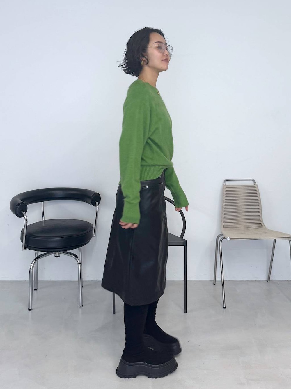 ブラック系のブーツ、グリーン系のニット/セーター、ブラック系のスカートを着用したレディースの秋コーディネートの3枚目の写真