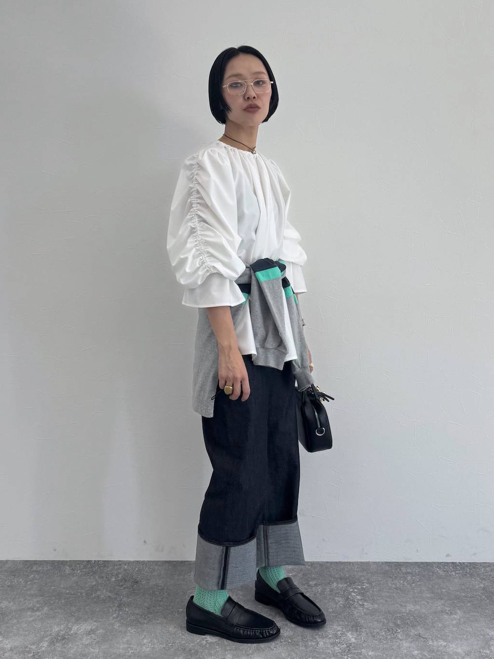 ブラック系のショルダーバッグ、ブルー系のデニムパンツを着用したレディースの冬コーディネートの3枚目の写真