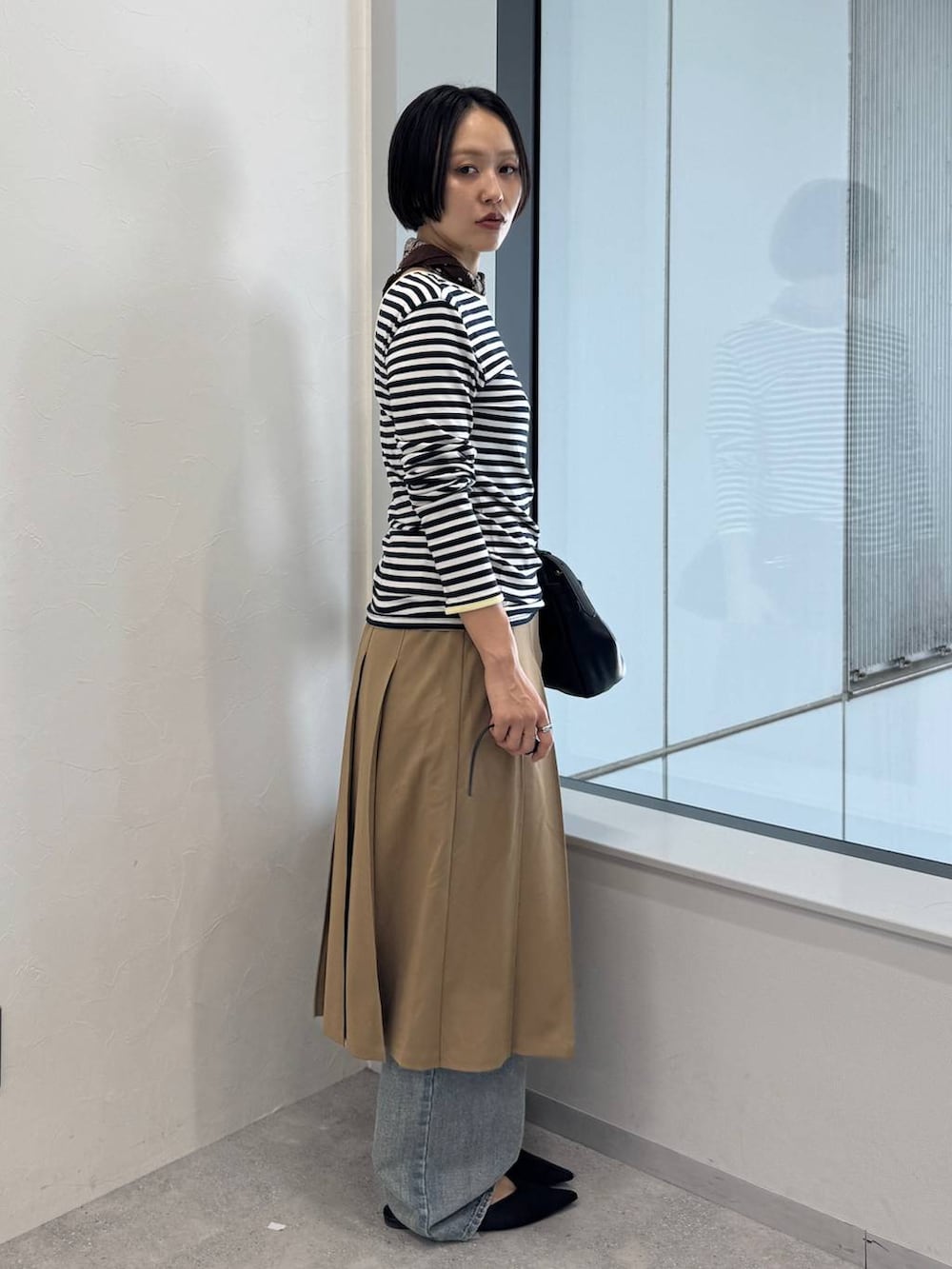 ブルー系のデニムパンツ、ブラック系のショルダーバッグ、ブラック系のサンダルを着用したレディースの夏コーディネートの2枚目の写真