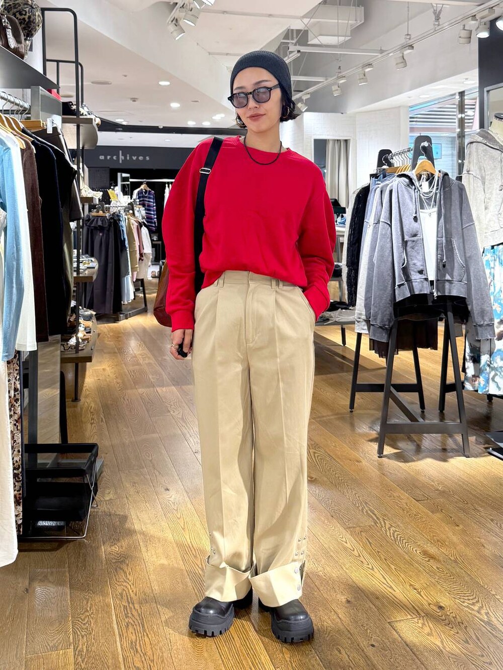 ブラウン系のショルダーバッグ、ブラック系のブーツ、ベージュ系のチノパンツを着用したレディースの秋コーディネートの5枚目の写真