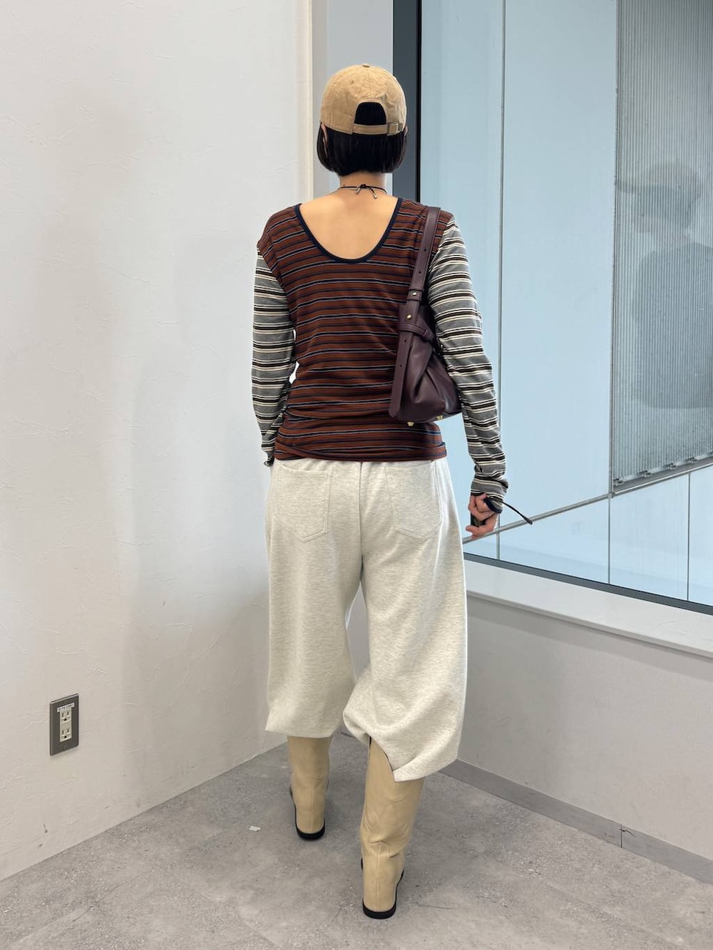 レッド系のショルダーバッグ、ホワイト系のブーツ、ベージュ系のスウェットパンツを着用したレディースの夏コーディネートの4枚目の写真