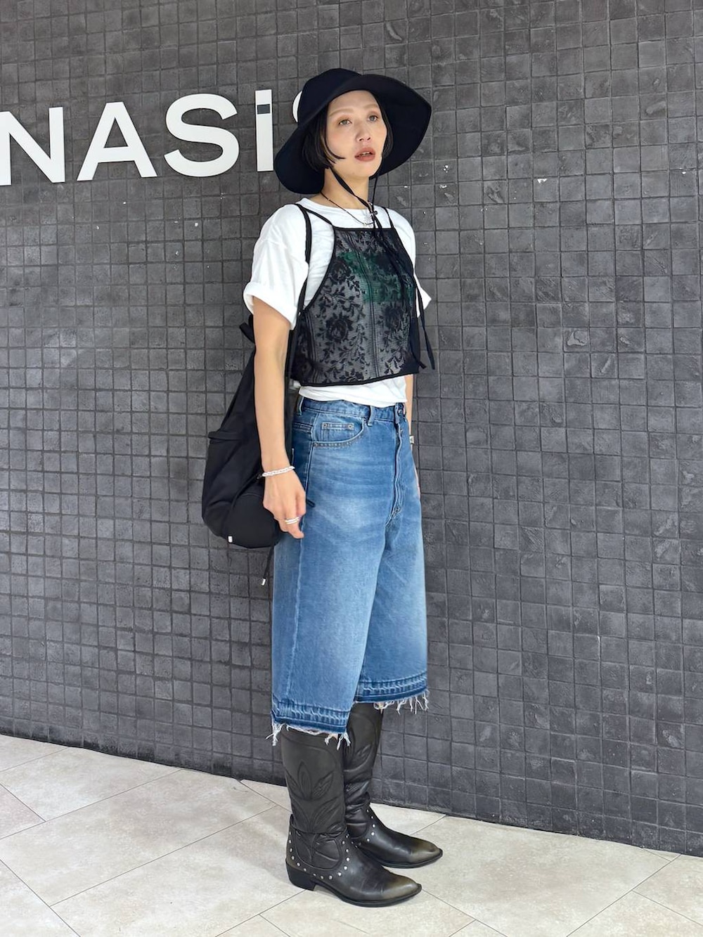 ホワイト系のTシャツ/カットソー、ブラック系のブーツ、ブルー系のデニムパンツを着用したレディースの夏コーディネートの3枚目の写真