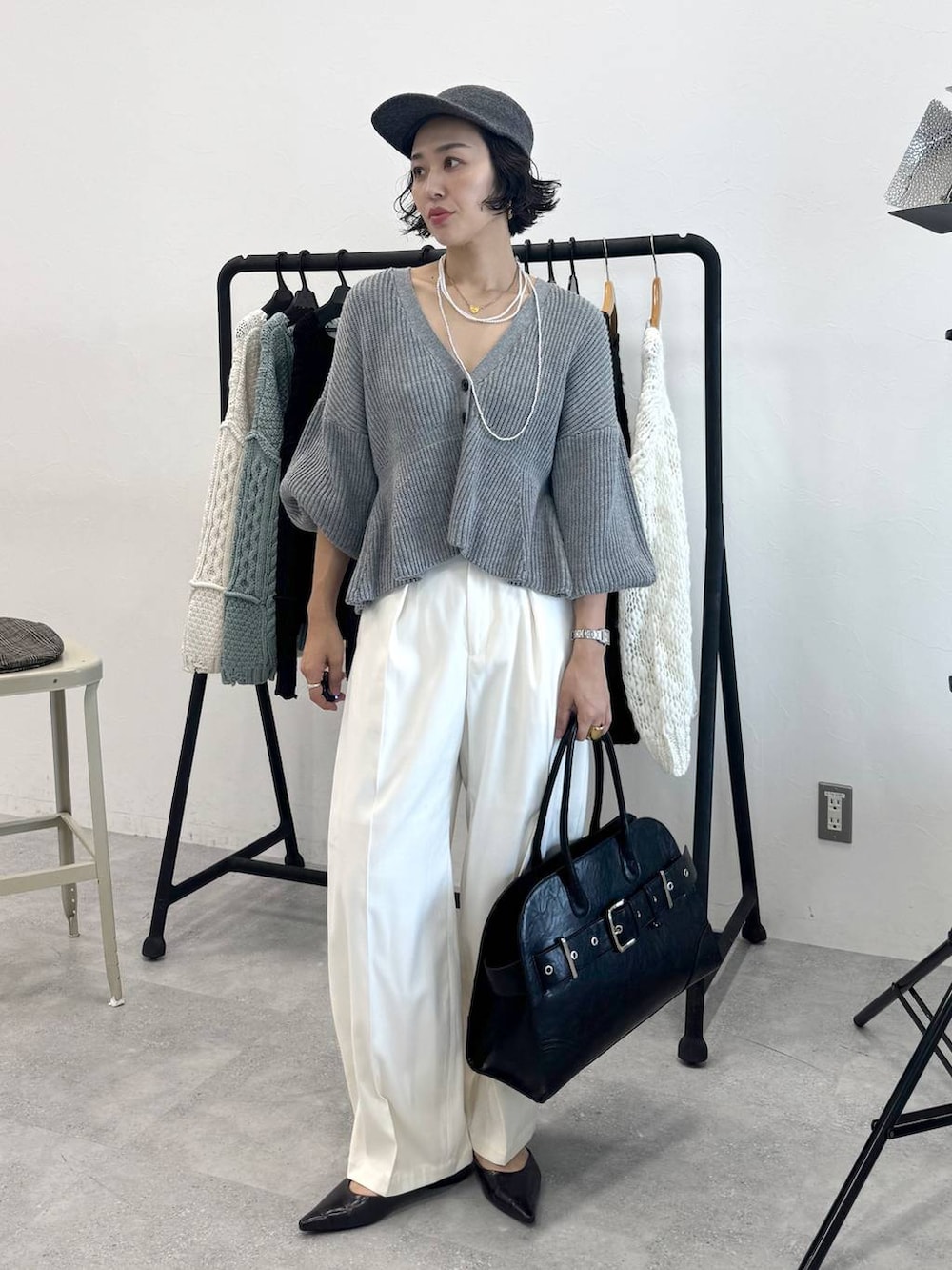 ホワイト系のスラックス、ブラック系のショルダーバッグ、グレー系のカーディガン/ボレロを着用したレディースの秋コーディネートの4枚目の写真