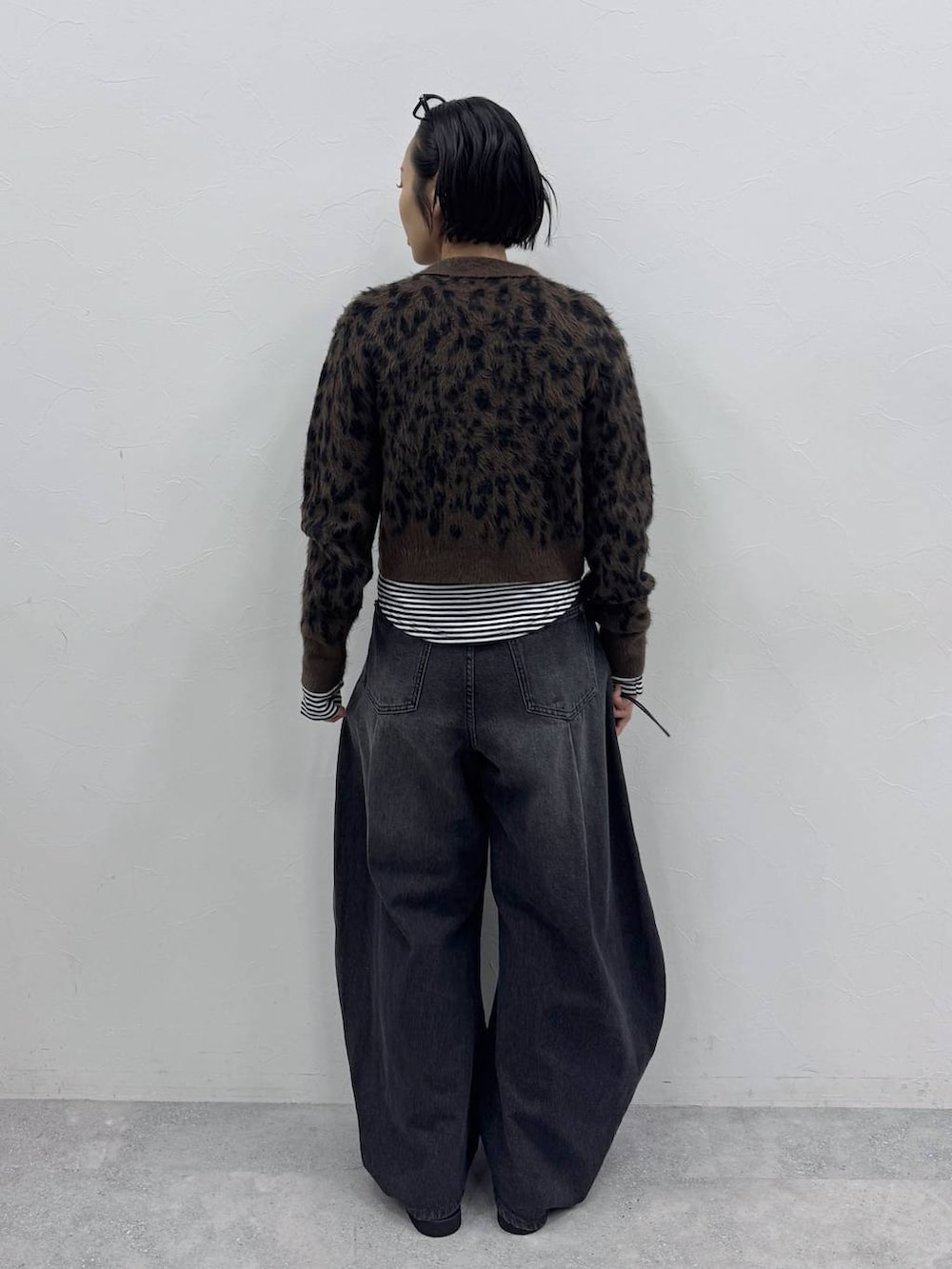 ブラック系のデニムパンツ、ブラウン系のカーディガン/ボレロ、ブラック系のTシャツ/カットソーを着用したレディースの秋コーディネートの3枚目の写真