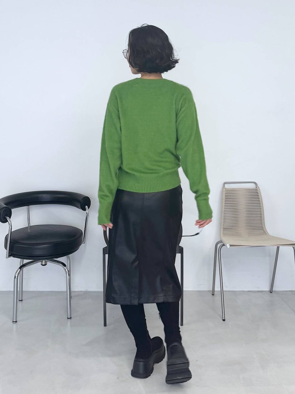ブラック系のブーツ、グリーン系のニット/セーター、ブラック系のスカートを着用したレディースの秋コーディネートの2枚目の写真